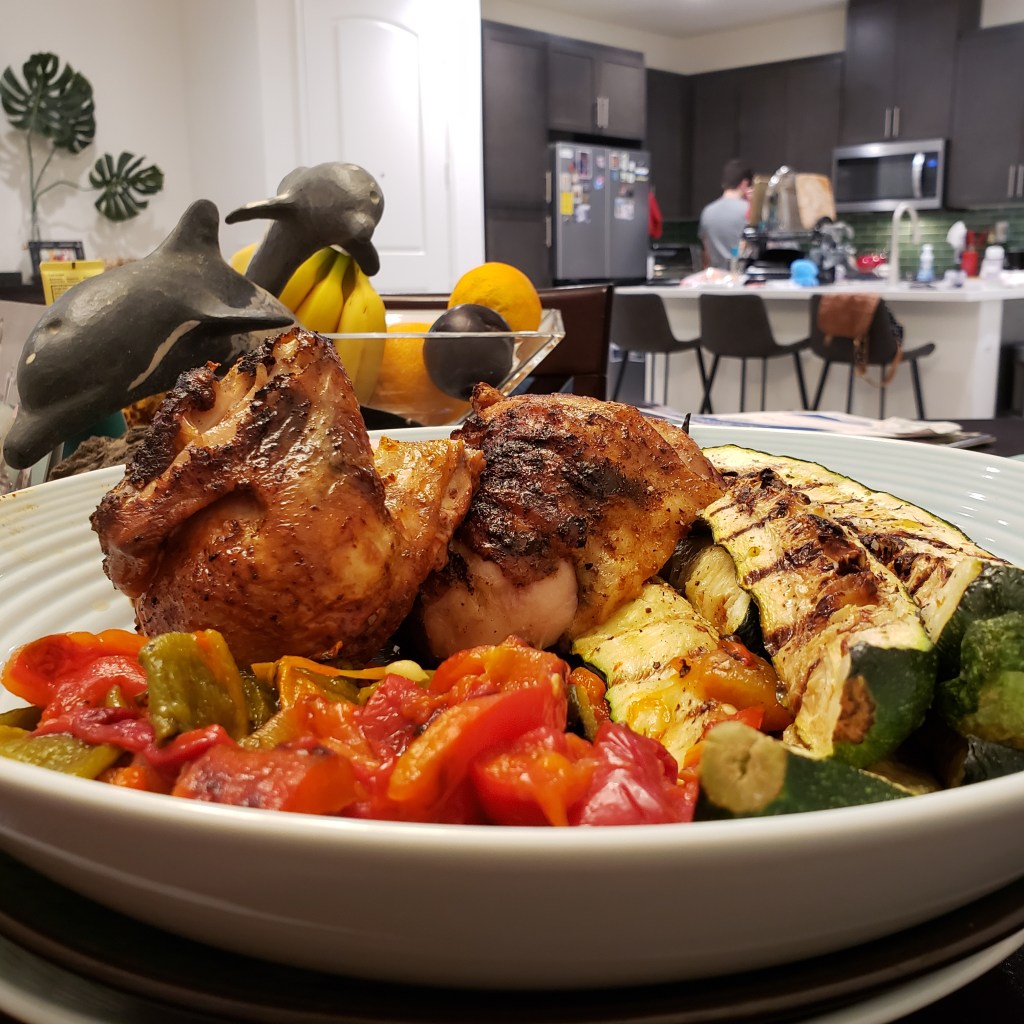 A plate of huli huli chicken, grilled zucchini and peppers. I'm in the far distance finishing up cooking in the kitchen.