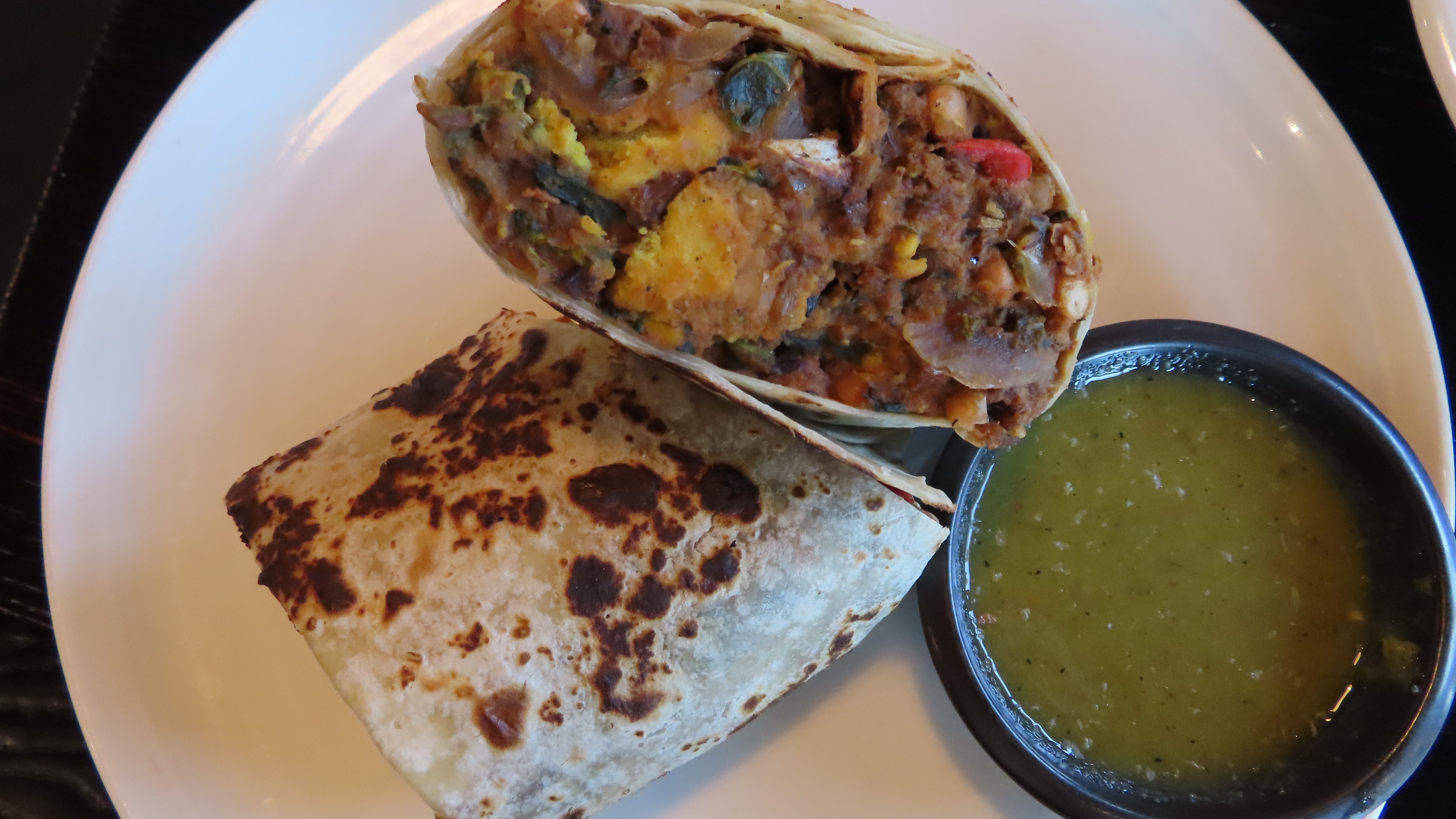 The breakfast burrito with a mild green salsa. There is a frittata made from a special flour mixture with chorizo made from wild rice and lentils and beans. The tortilla is crisped and served handsomely on a white plate.